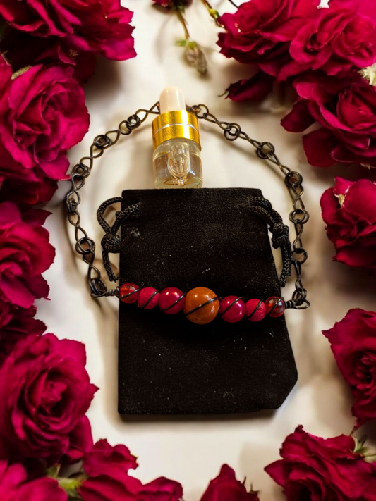 Handcrafted red agate diffuser bracelet with red lava beads, resin pearls, and black hypoallergenic wire with infinity links, displayed on a black velvet pouch surrounded by red roses.