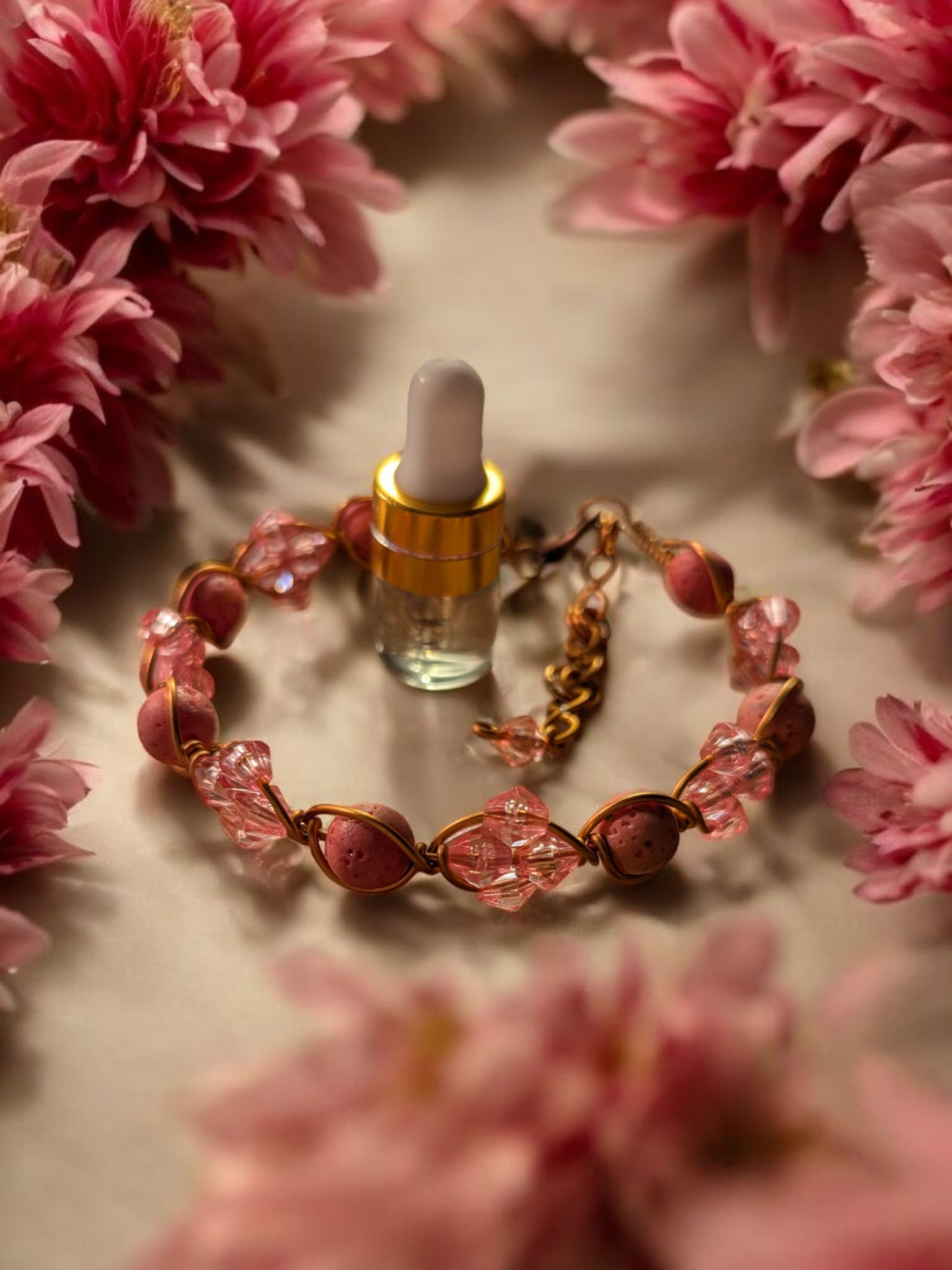 Pink lava and copper diffuser cuff bracelet with blush crystal accents surrounded by soft pink flowers
