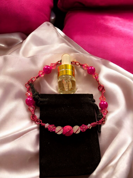 Handcrafted pink lava diffuser bracelet with white jade beads, pink resin accents, and pink hypoallergenic wire, displayed on a black velvet pouch atop soft pink satin.